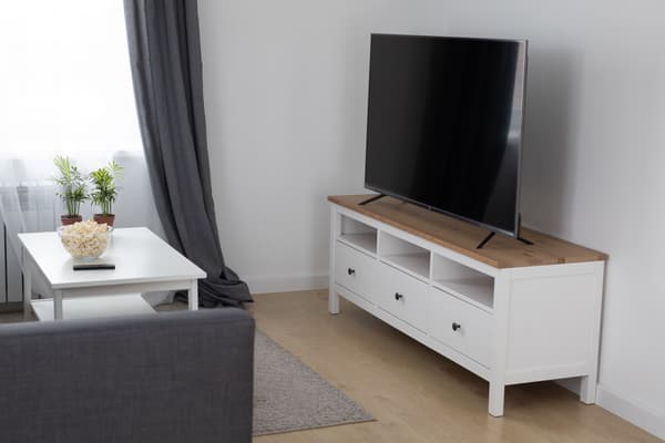 Fernseher auf einem weißen Sideboard in einem hellen Wohnzimmer